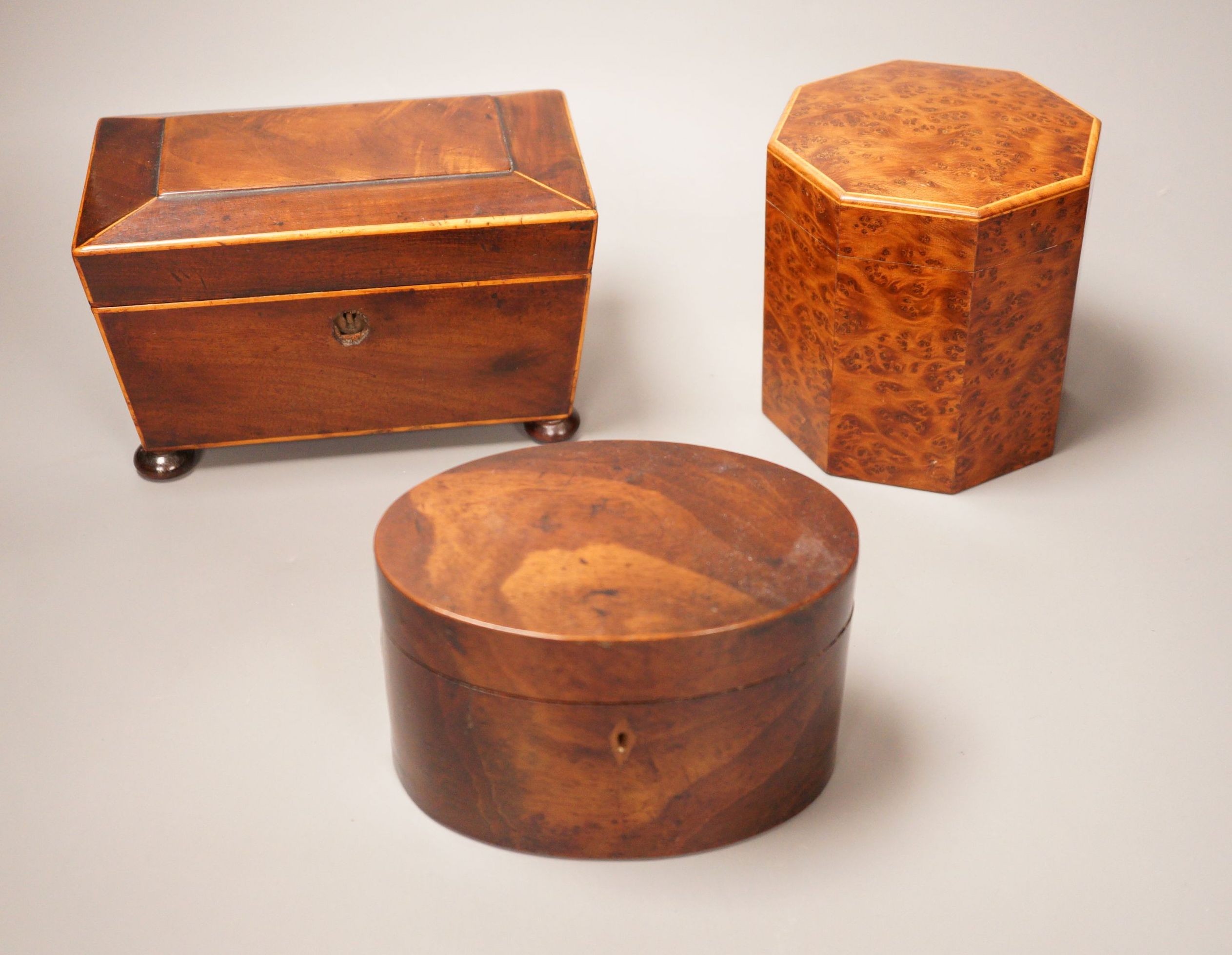 An oval mahogany box (with key), an octagonal amboyna tea caddy and a boxwood edged mahogany tea caddy, 19th century 20cm wide